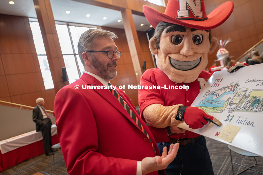 Herbie Husker is with Chancellor Ronnie Green looking at a display of the $1 cost to attend UNL and points to a post-it note asking if we could go back to that tuition. Everyone was invited to enjoy a cupcake and join in the festivities with their Husker friends at the Wick Alumni Center, Friday February 15th. The Nebraska Charter was available to view, along with other historical items. Copies of Dear Old Nebraska U could be purchased and signed. Charter Day at the Wick Alumni. February 15th, 2019. Photo by Gregory Nathan / University Communication.
